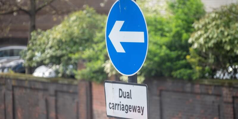 Dual carriageway sign with blue arrow direction sign above